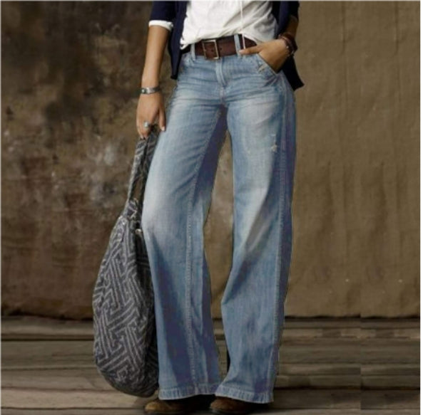 Femme portant un pantalon en jean droit bleu clair à coupe moderne, taille moyenne avec passants de ceinture, jambes longues et droites, offrant une allure décontractée et élégante, associé à une tenue casual chic et un sac porté à la main.